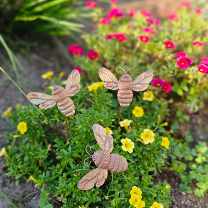 Rustic metal bee garden stakes in flowering garden bed